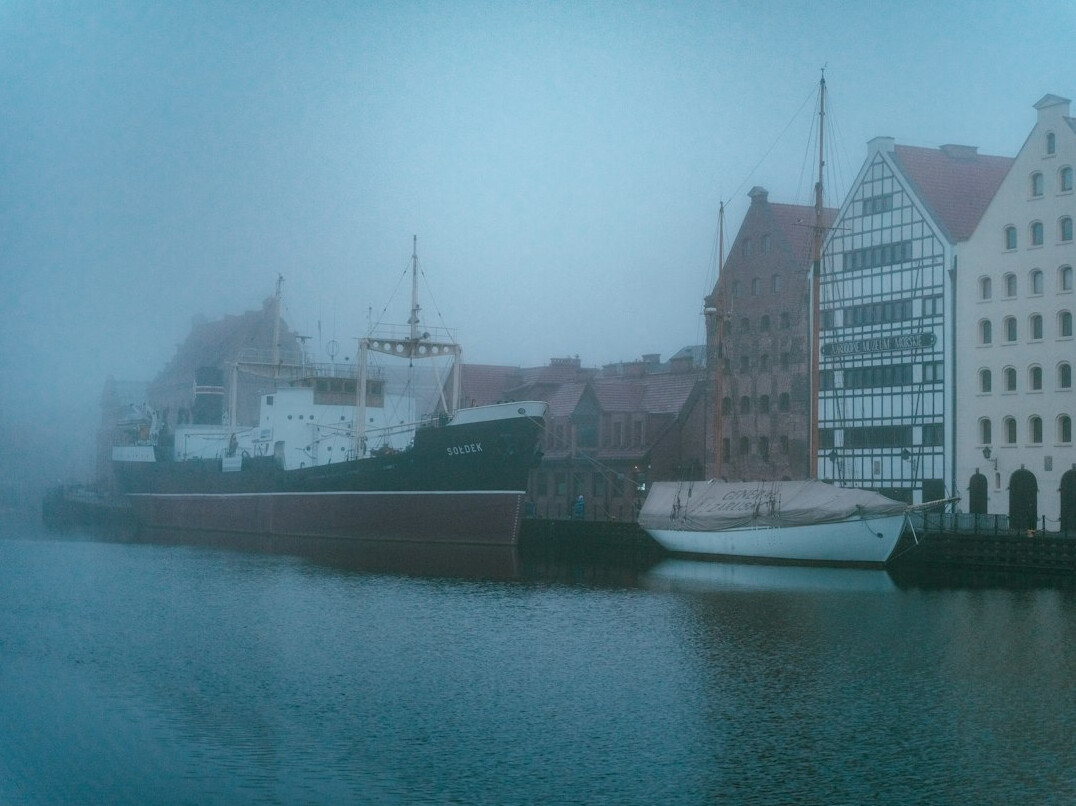 Foggy harbor at dusk with old buildings